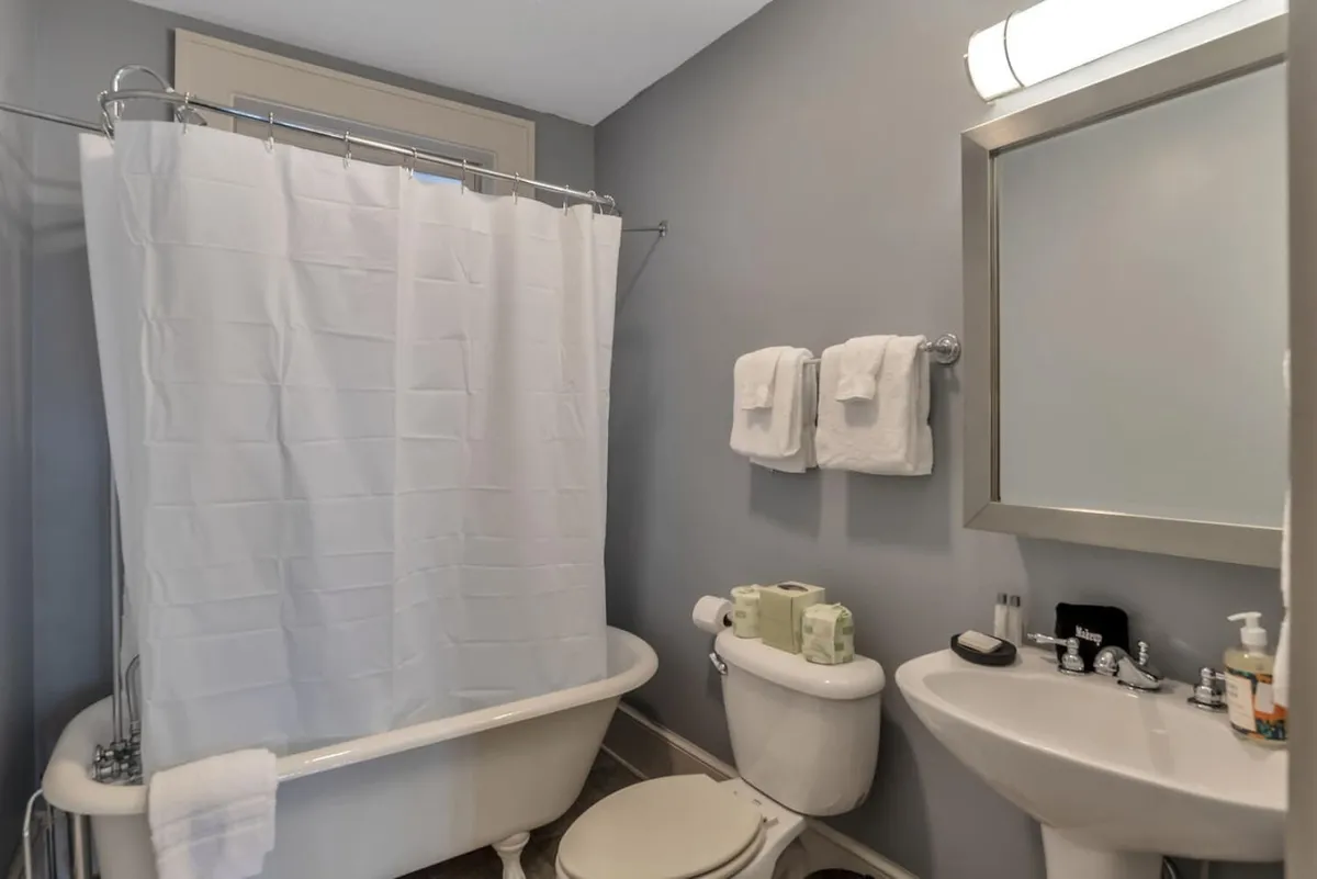 A modern bathroom featuring a gleaming bathtub, contemporary sink, toilet, and plush towels. The space is bright and refreshing, conveying a sense of cleanliness and modern comfort—ideal for a soothing bath or efficient morning routine.